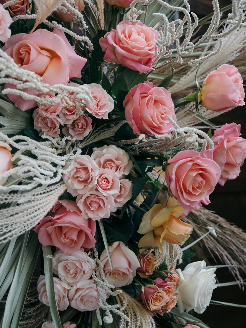 Detail of floral wedding arbor with dried grasses