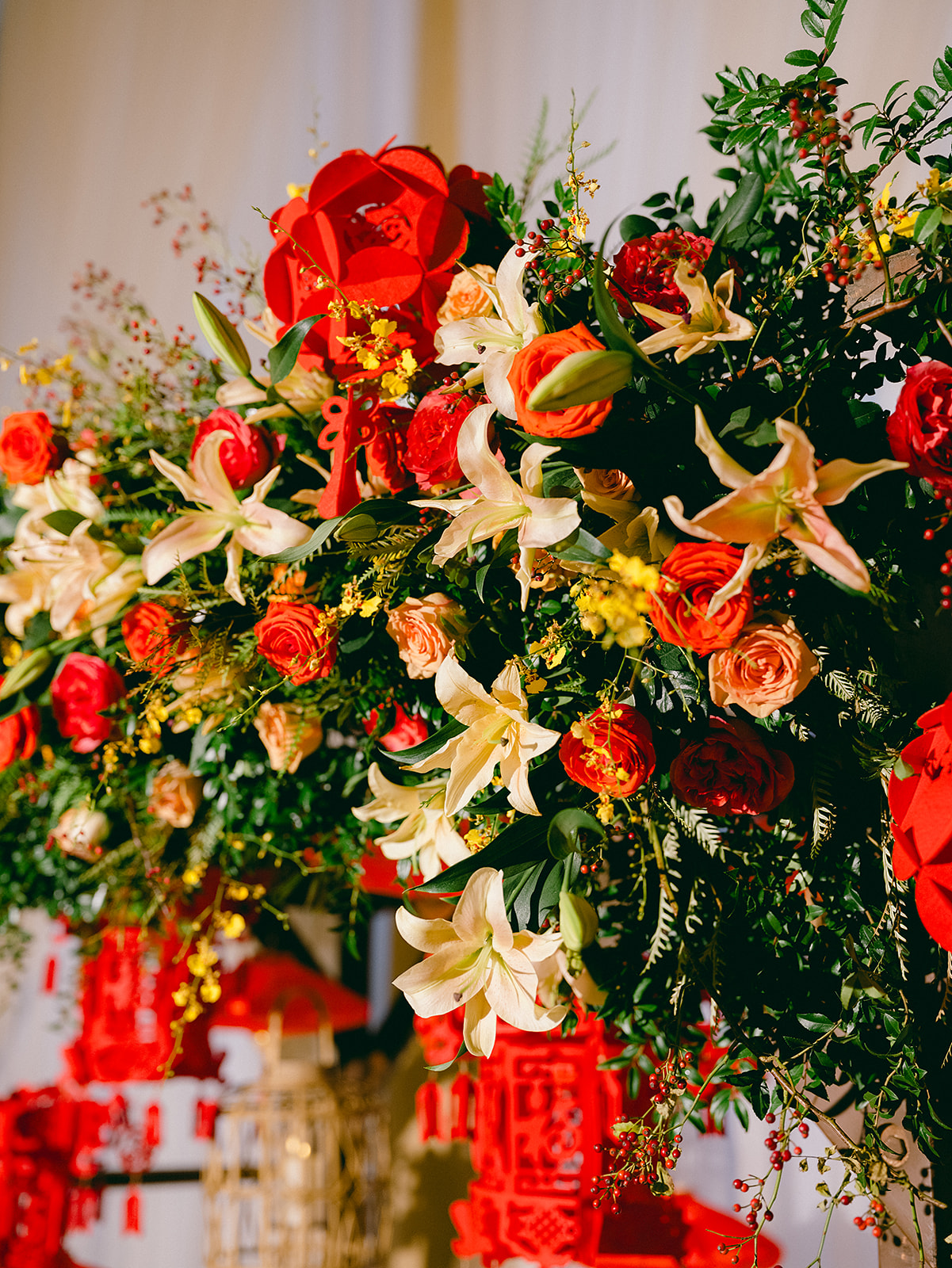 Detail photograph of wedding ceremony flower installation in red, yellow, and orange.