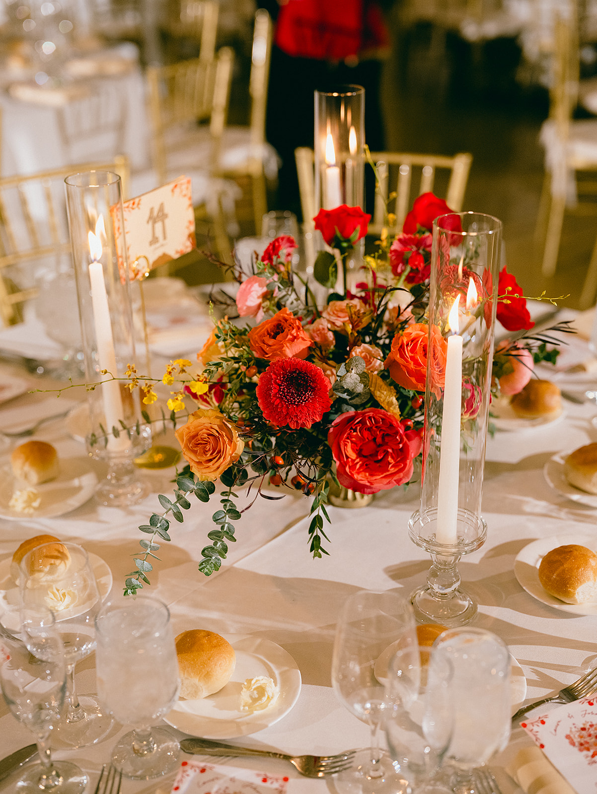 Pedestal vase wedding flowers centerpiece in red, orange, and yellow.