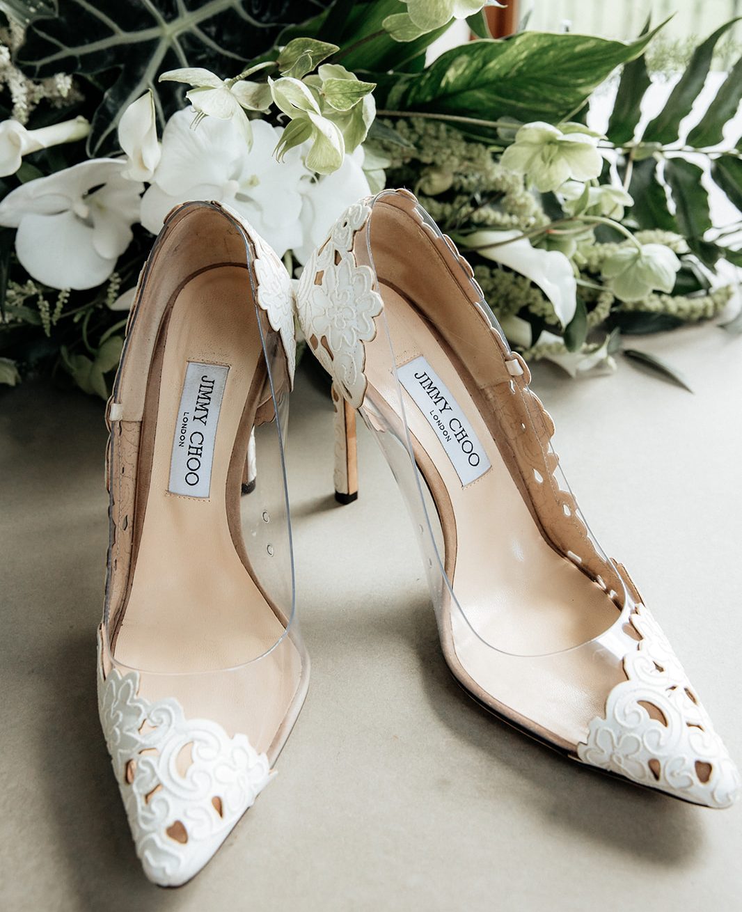 Detail of bridal shoes and wedding bouquet of mixed tropical foliage and white orchids.