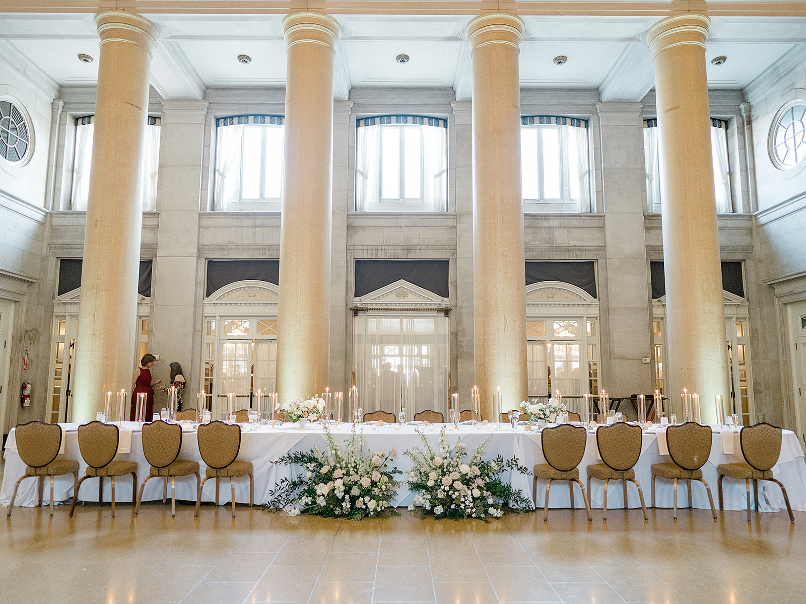 Hall of Springs wedding head table with chairs in front of soaring columns and windows. 