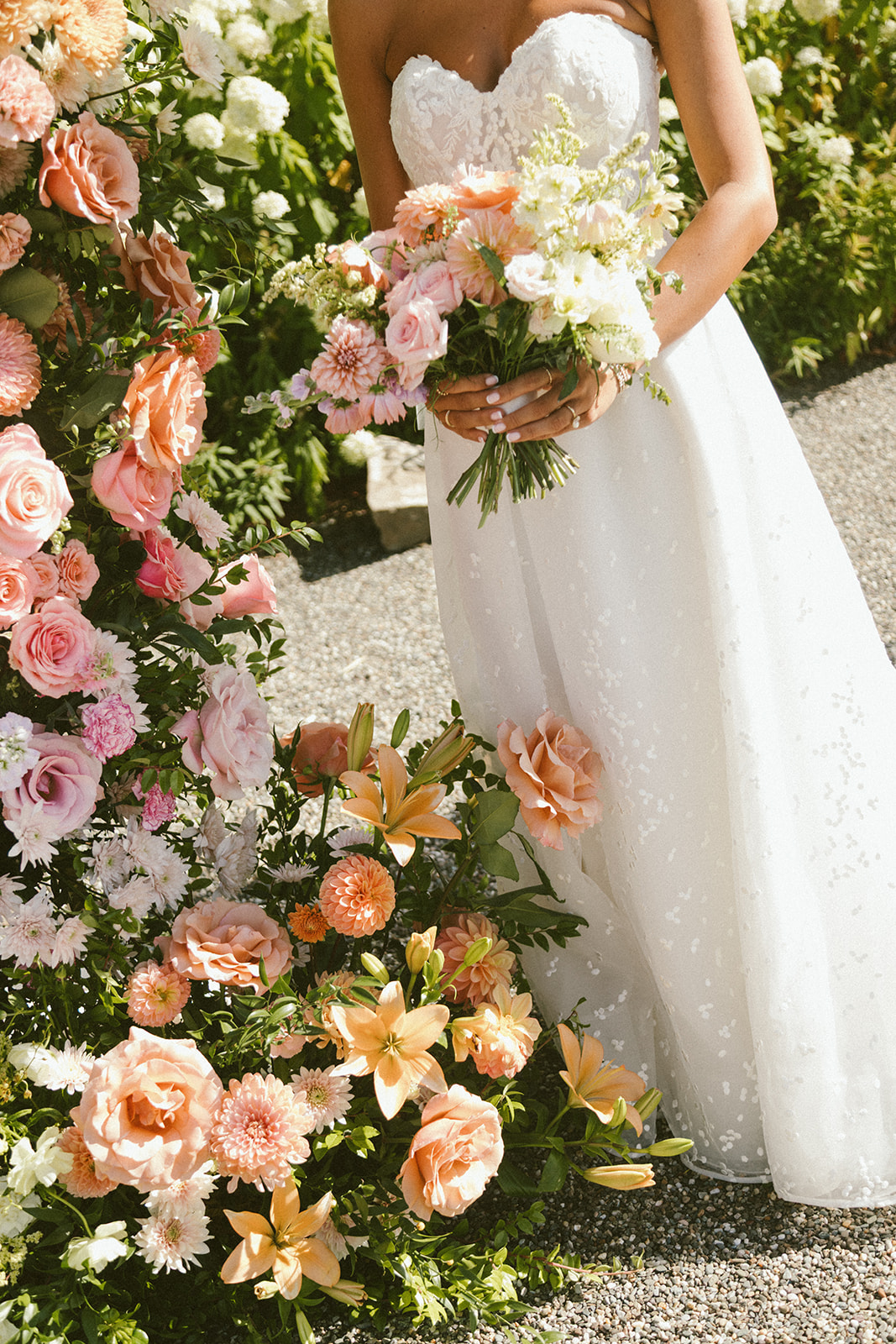 Wedding ceremony detail of open floral wedding arch in sunset palette.