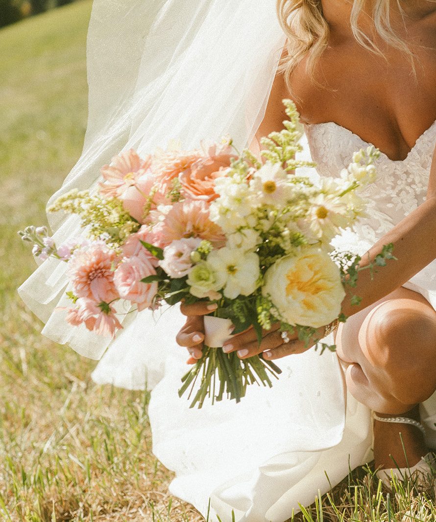 Detail of bridal bouquet in sunset palette with garden roses, ranunculus, and dahlias.