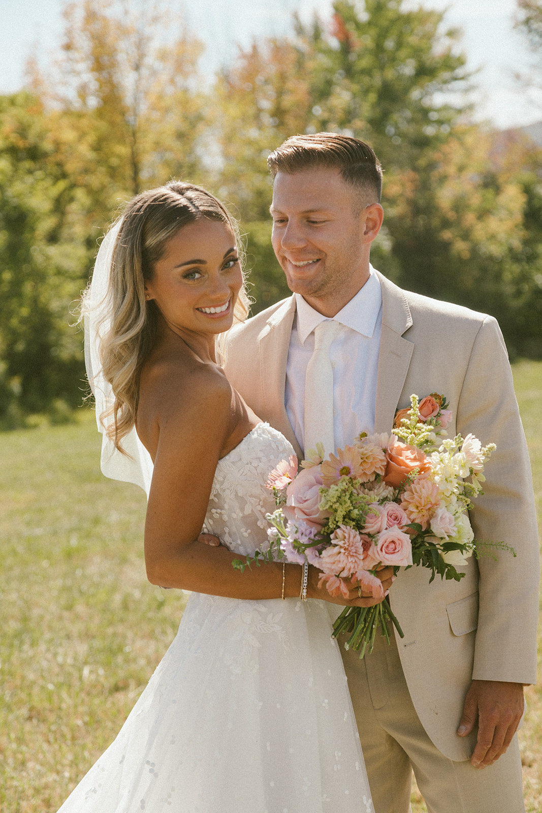Bride and groom with wedding bouquet in sunset palette.