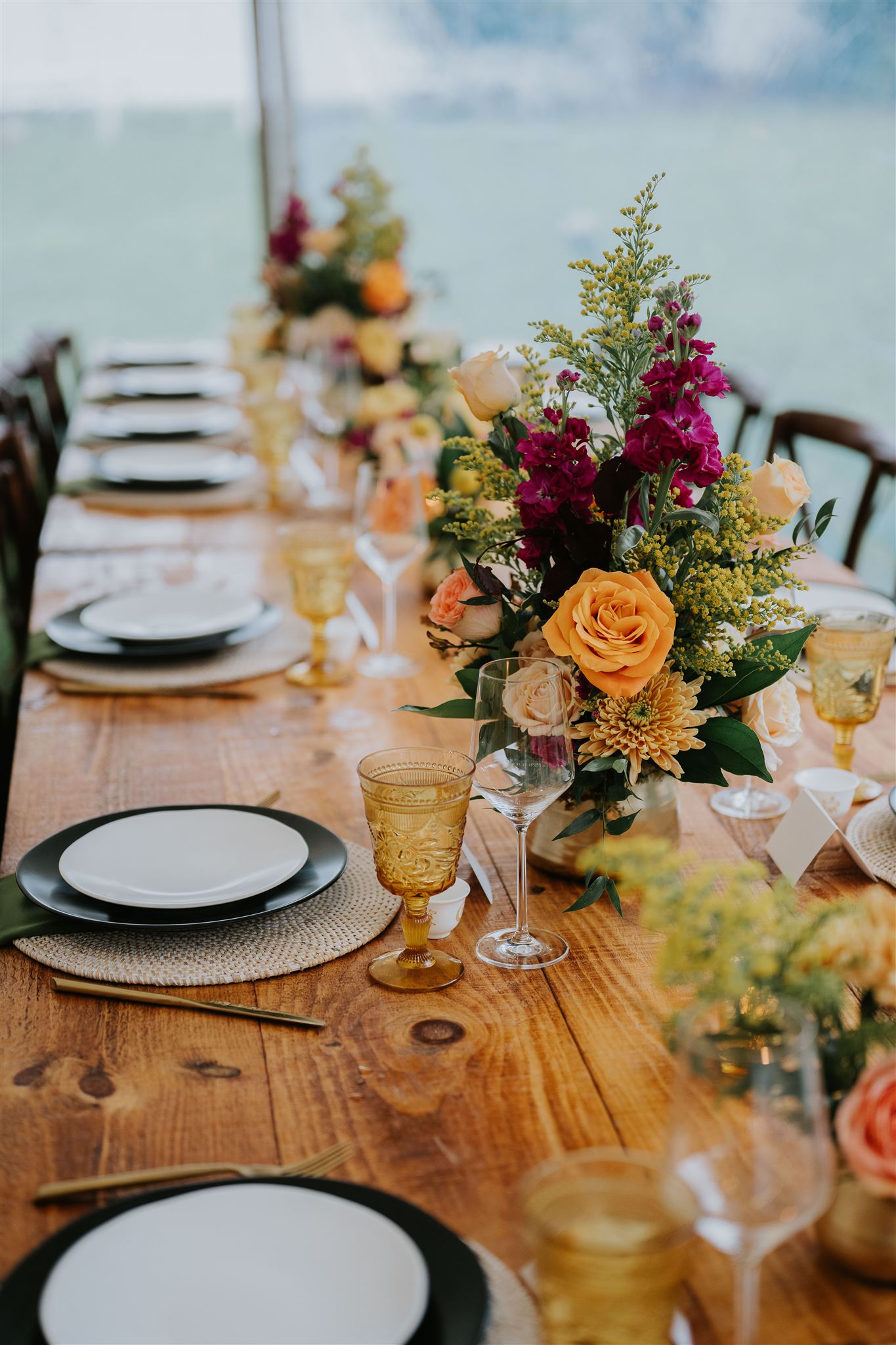 A long wedding reception table set with floral arrangements and place settings.