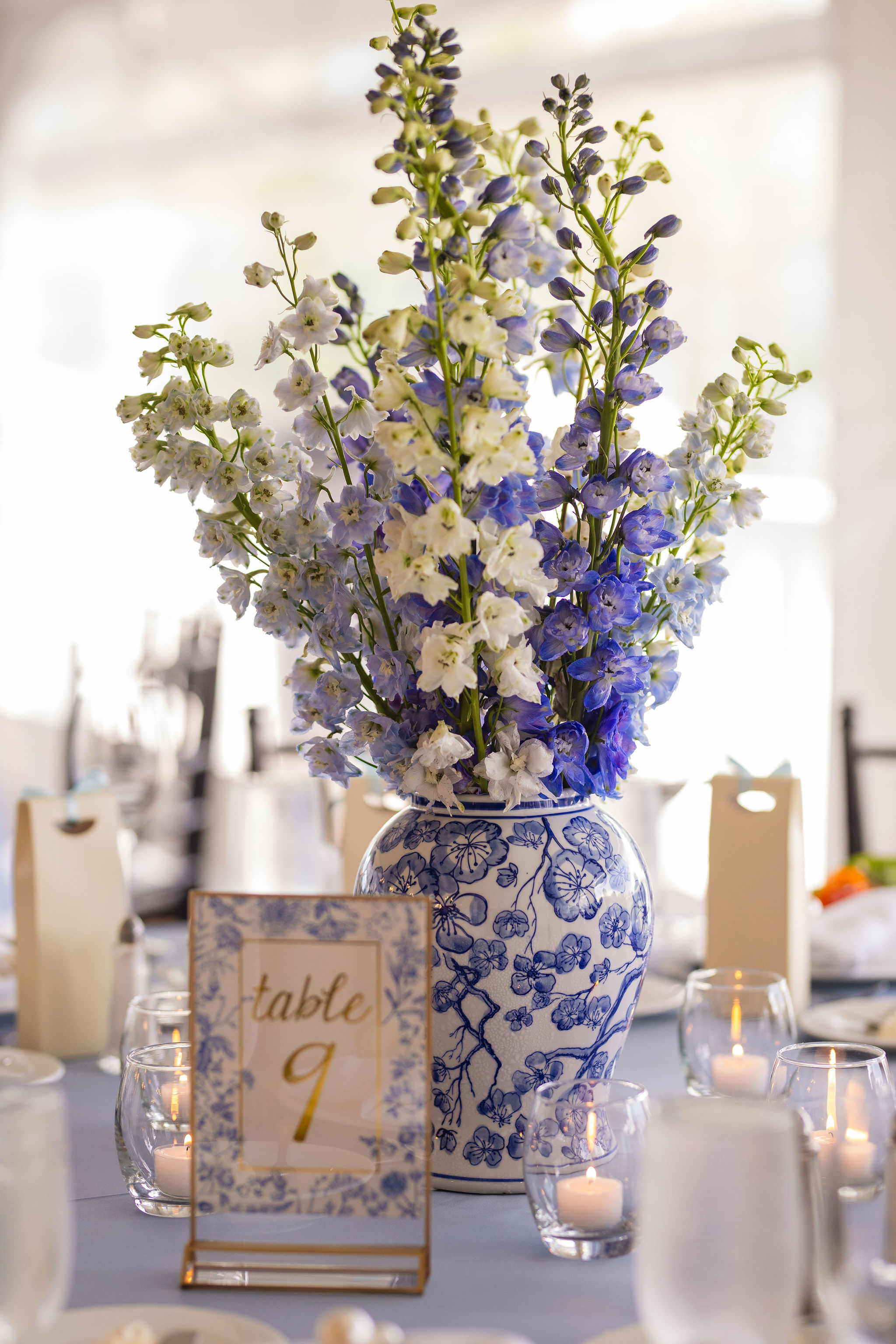 A blue and white urn with blue and white delphiniums shown as a wedding reception centerpiece at The Sagamore Resort.